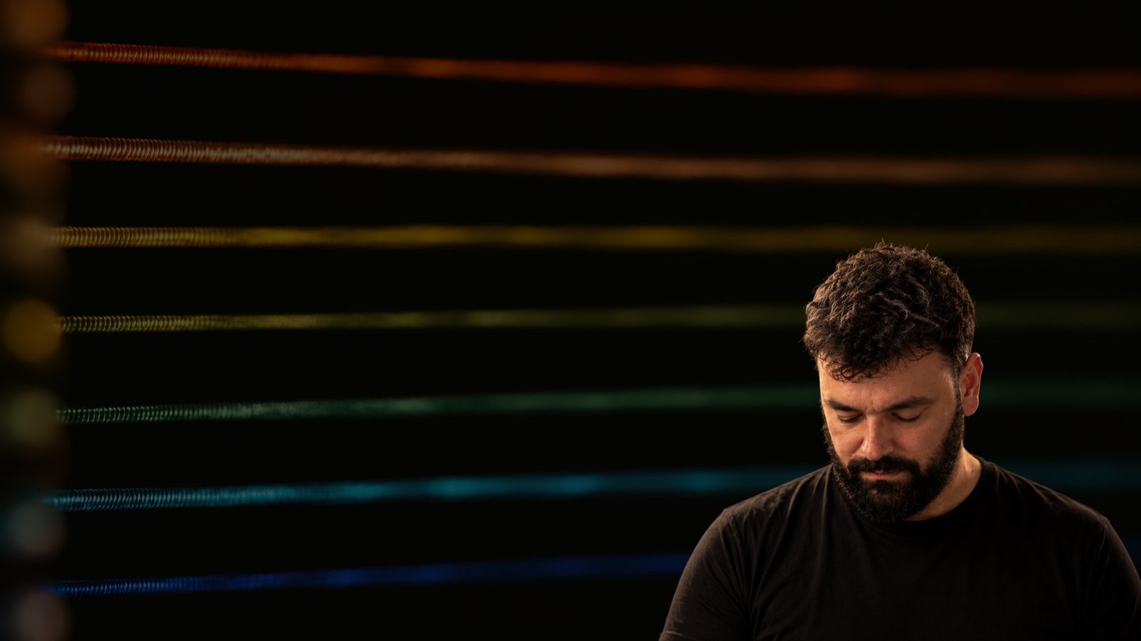 Pietro Gallo seated behind horizontal illuminated strings